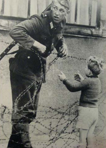 Voják by neměl nechat projít dítě na druhou stranu berlínské zdi. Ono však ztratilo celou svou rodinu. Voják je zachycen, jak chlapečkovi pomáhá přejít na druhou stranu.